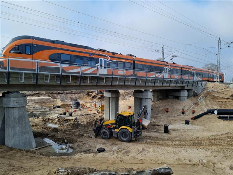 Road construction works under an bridge with a train